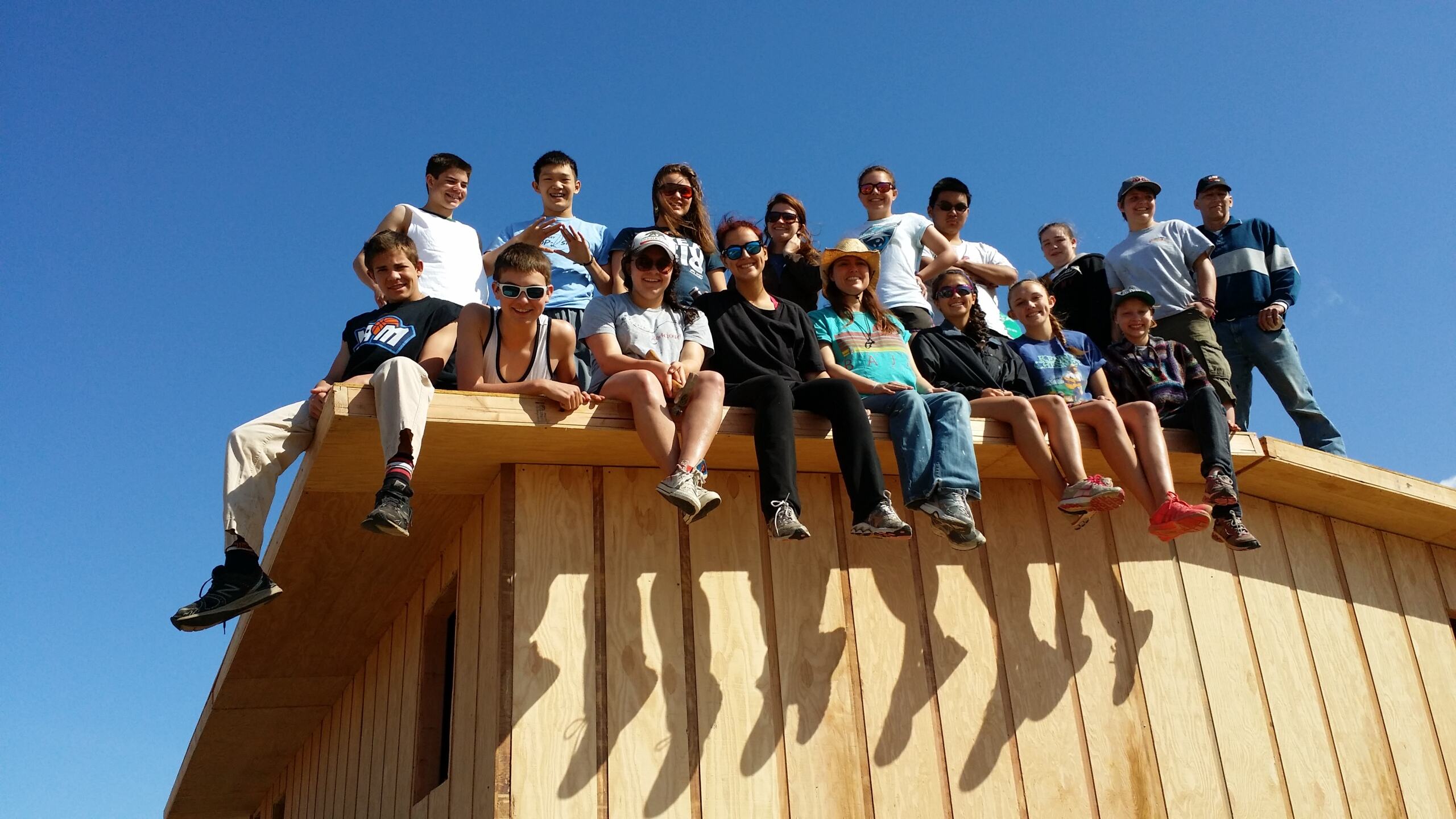 Group of students sitting on atop of a house they helped build for Student Reach Baja!